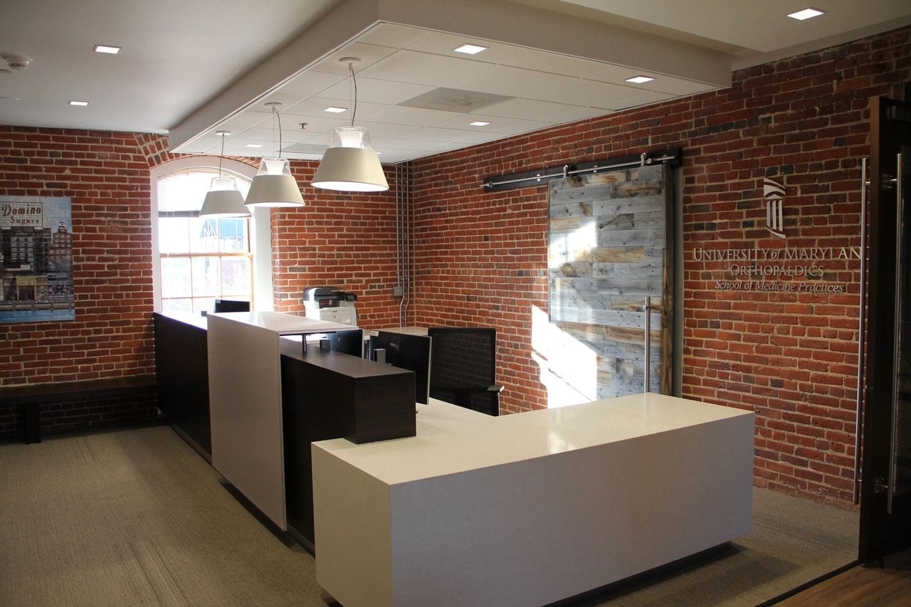 office desks and chairs in front of a brick wall